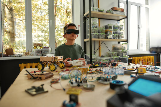 Discover What Is Possible. Child programming, testing robot vehicle, using console controller, working with wires and circuits at stem class.