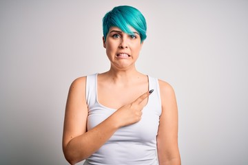 Obraz na płótnie Canvas Young beautiful woman with blue fashion hair wearing casual t-shirt over white background Pointing aside worried and nervous with forefinger, concerned and surprised expression