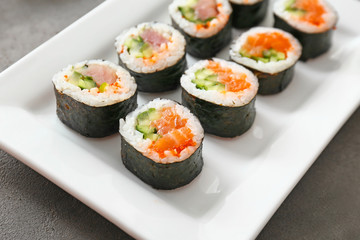 Plate with tasty sushi rolls on table
