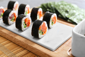 Board with tasty sushi rolls on table