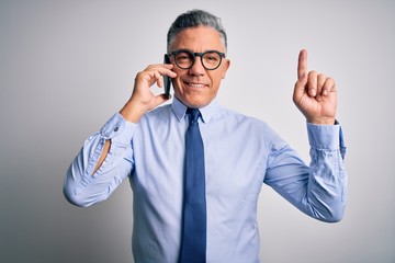 Middle age handsome grey-haired business man having conversation talking on the smartphone surprised with an idea or question pointing finger with happy face, number one