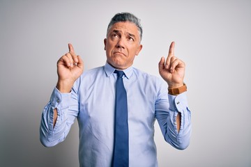 Middle age handsome grey-haired business man wearing elegant shirt and tie Pointing up looking sad and upset, indicating direction with fingers, unhappy and depressed.