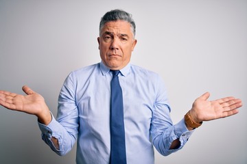Middle age handsome grey-haired business man wearing elegant shirt and tie clueless and confused with open arms, no idea concept.