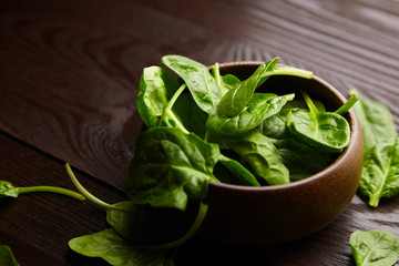 Spinach fresh green leaves in a wooden bowl