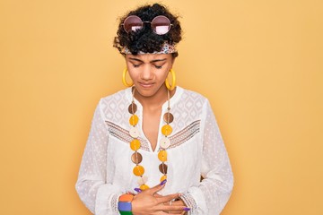 Young beautiful african american afro hippie woman wearing sunglasses and accessories with hand on stomach because indigestion, painful illness feeling unwell. Ache concept.