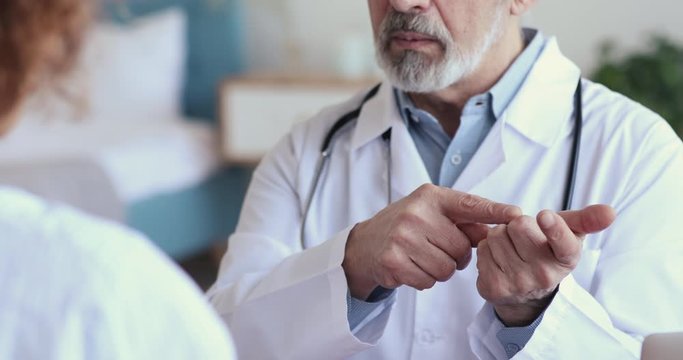 Doctor advice concept. Older male doctor physician wears white coat consulting adult woman patient explaining treatment, prescribing recipe, giving medical healthcare recommendations. Close up view