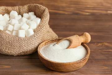 Sack and plate with sweet sugar on wooden background