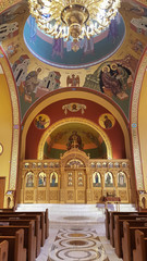 Fototapeta na wymiar Aisle, stage and ornate celing with chandelier of a Greek Orthodox church