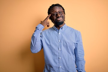 Young handsome african american man wearing shirt and glasses over yellow background Shooting and killing oneself pointing hand and fingers to head like gun, suicide gesture.