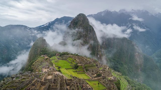 Zoom in time lapse view of mysterious Inca ruins of Machu Picchu shrouded in mist high in the Andes mountain range, Cusco Region, Peru.