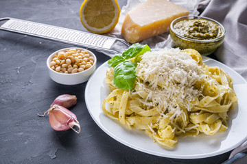 Delicious tagliatelle pasta with pesnto sauce on dark stone background