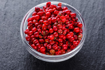 pink peppercorns on a dark stone background