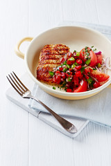 Grilled Turkey Breast with tomatoe salad. Bright wooden background.. Copy space.