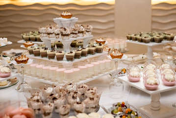 Sweet table for birthday or wedding ceremony. Candy bar with a lot of different candies and sweet cakes. Selective focus. Party and holiday celebration concept