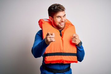 Young blond tourist man with beard and blue eyes wearing lifejacket over white background pointing...