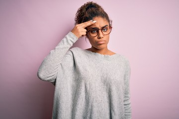 Young beautiful african american girl wearing sweater and glasses over pink background worried and stressed about a problem with hand on forehead, nervous and anxious for crisis