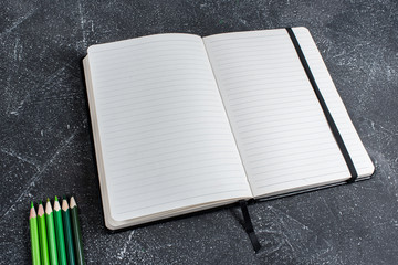 Green pencils and notebook on a black stone table