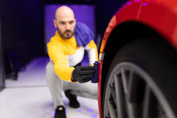 Car detailing - Worker polishing car in auto repair shop. Selective focus.