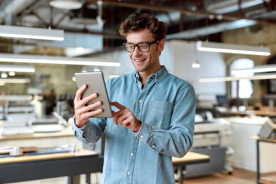 Work and have fun. Young businessman posing in office