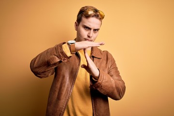 Young handsome redhead man wearing casual leather jacket over isolated yellow background Doing time...