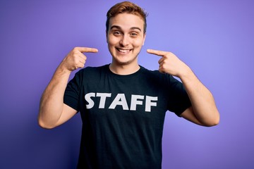 Young handsome redhead worker man wearing staff t-shirt uniform over purple background smiling cheerful showing and pointing with fingers teeth and mouth. Dental health concept.