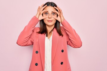 Young beautiful brunette businesswoman wearing elegant jacket over isolated pink background Trying...