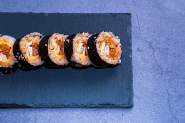 Kimchi kimbap with omelette on a slate place on concrete background. Korean cuisine.