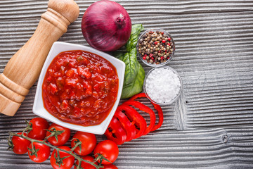 Fresh tasty tomato sauce on rustic wooden background