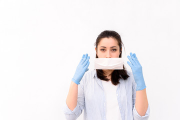 Girl paramedic in medical gloves is puts a protective medical mask on her face on a white background