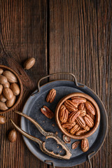 Healthy snack rich in vitamins and minerals, fresh shelled and in-shell pecans in a bowl with copy space
