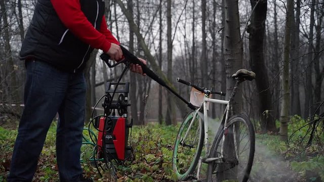 A man washes his bike in the woods with hi pressure