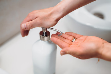 woman using soap dispenser for washing hands during wordwide pandemic, coronavirus