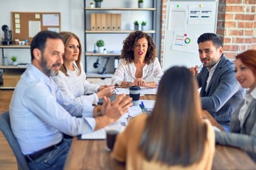 Group of business workers working together. Sitting on desk speaking at the office