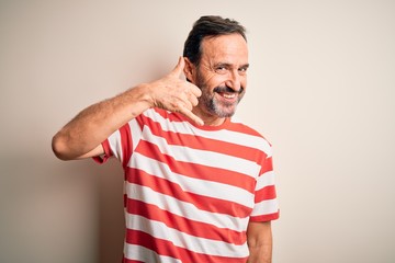 Fototapeta premium Middle age hoary man wearing casual striped t-shirt standing over isolated white background smiling doing phone gesture with hand and fingers like talking on the telephone. Communicating concepts.