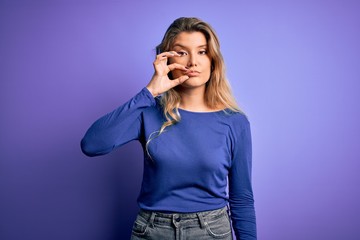Young beautiful blonde woman wearing casual t-shirt over isolated purple background mouth and lips...