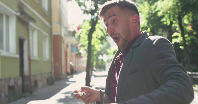 Unhealthy man sneezes and sprays nose and into camera with nasal spray on street