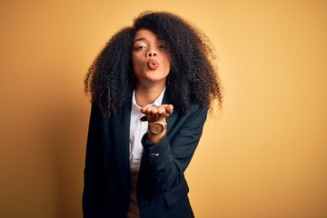 Young beautiful african american business woman with afro hair wearing elegant jacket looking at...