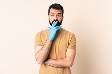 Caucasian man with beard protecting from the coronavirus with a mask and gloves over isolated background surprised and shocked while looking right