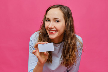 Stylish caucasian girl in a pale blue t-shirt holding a white card in his hands and looking at the...