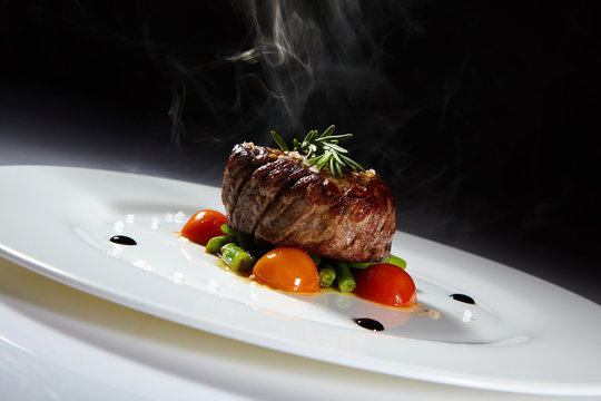 Appetizing stake on white plate. Grilled meat with vegetables