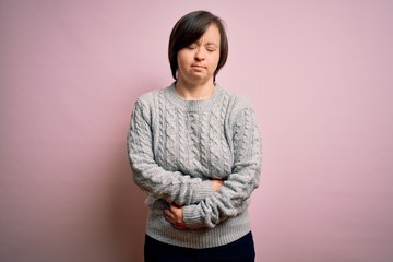 Fototapeta premium Young down syndrome woman wearing casual sweater over isolated background with hand on stomach because indigestion, painful illness feeling unwell. Ache concept.