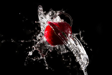 The water splashes the apple on the water until it spreads beautifully on a black background.