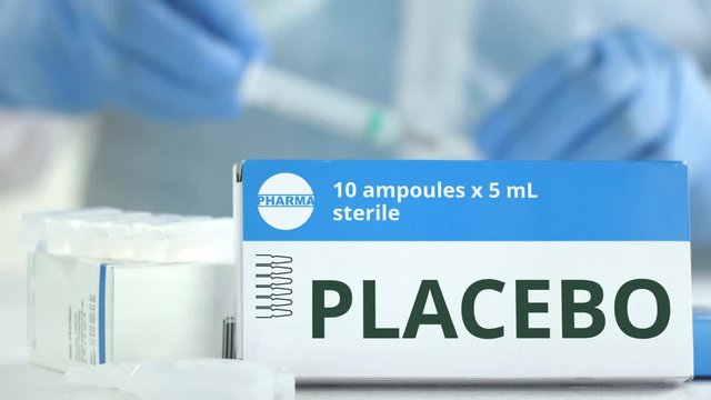 Box with placebo medicine on the table against blurred lab assistant. Fictional phaceutical logo