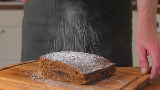 Man using sugar shaker on classic gingerbread in traditional kitchen. A classic gingerbread recipe. Family home bakery, cooking traditional festive sweets. Man cooking food.