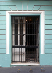 Steal gated entrance set into a mint green wall with white trim along the cobblestone sidewalks of old town San Juan.