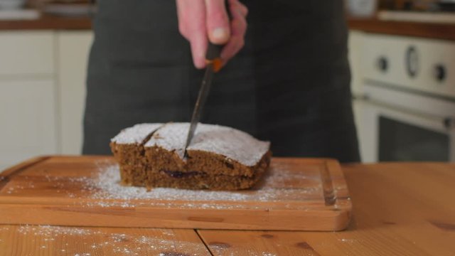 Man cutting classic gingerbread in traditional kitchen. A classic gingerbread recipe. Family home bakery, cooking traditional festive sweets. Man cooking food.