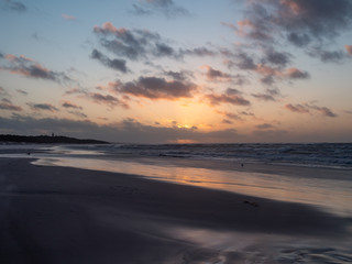 Fototapeta na wymiar Sunset over Baltic Sea, empty beach, waves on the sea. Shot during windy weather. Leba, Poland.