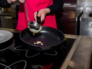 The process of making pancakes. Cook in the kitchen makes the dough
