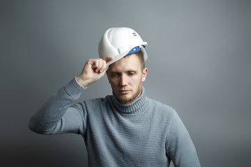 Man worker takes off the white construction helmet