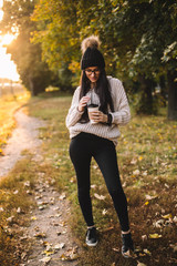 Young trendy woman blogger with coffee in park